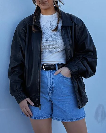 90s style clothing with a black leather jacket, white tee and denim shorts