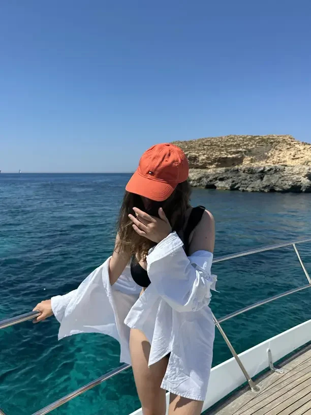 Best Christmas gifts for boaters with a woman in a red cap relaxing on a boat on blue water.