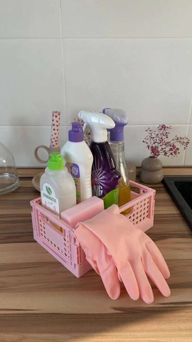 Pink cleaning caddy with spray bottles, a brush and pink rubber gloves