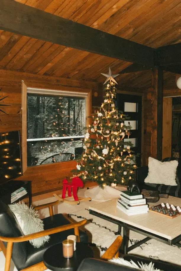 Christmas gift ideas for an 80 year old man with a cozy cabin living room and a lit Christmas tree.