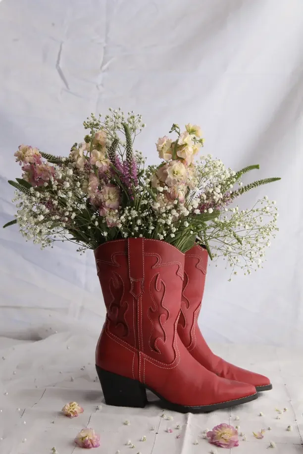 Christmas gift ideas for a country girl with red cowboy boots holding a bouquet of flowers.