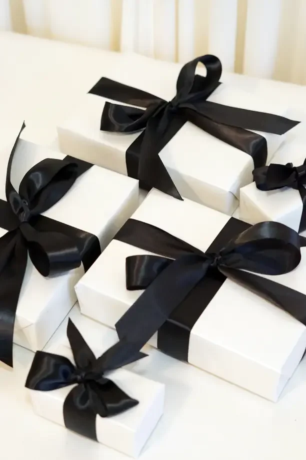 Christmas gift ideas for parents who have everything with white gift boxes tied with black bows.