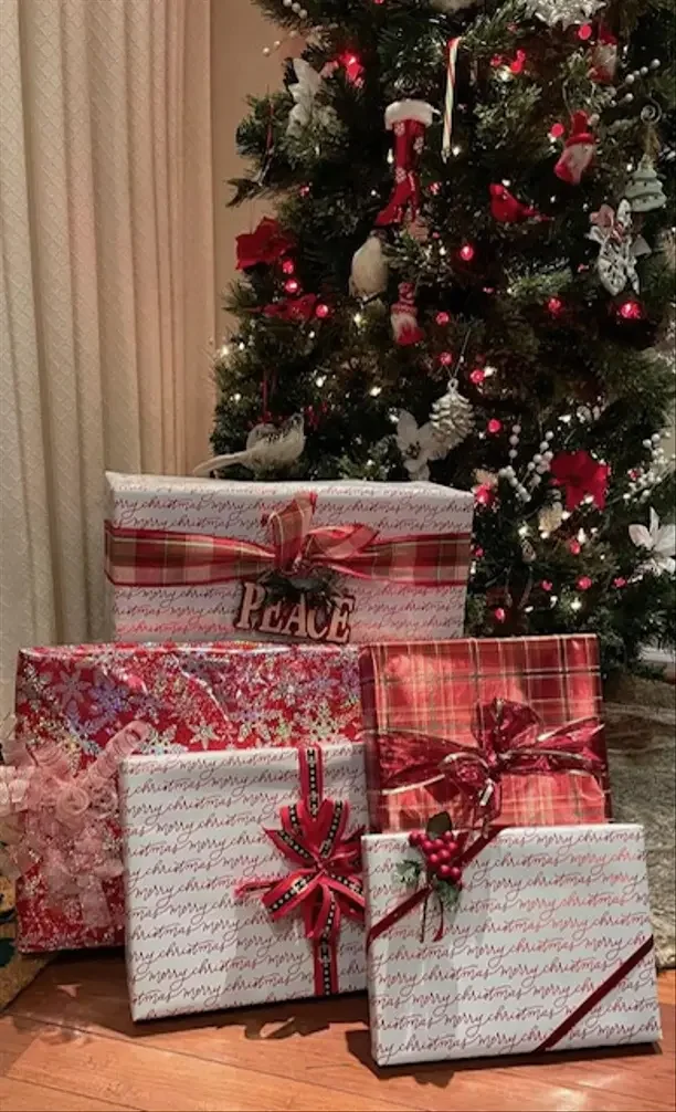 Christmas gifts for family far away with red and white wrapped presents under a Christmas tree.