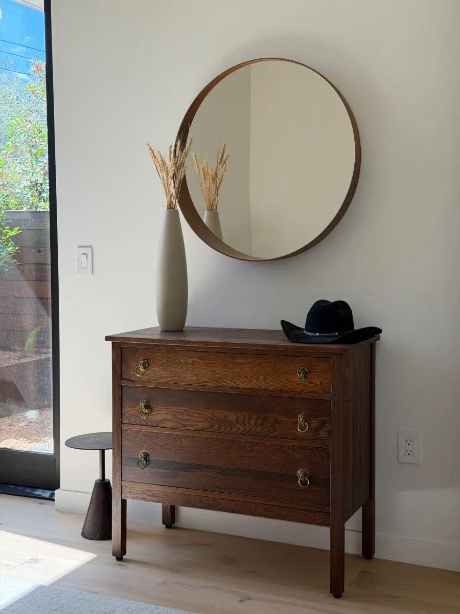 round mirror above an antique wood dresser