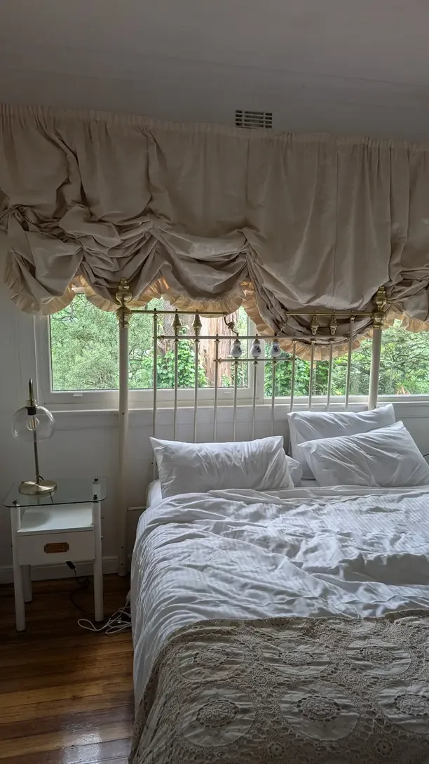 French country bedroom with a white nightstand, iron bed and a balloon shade