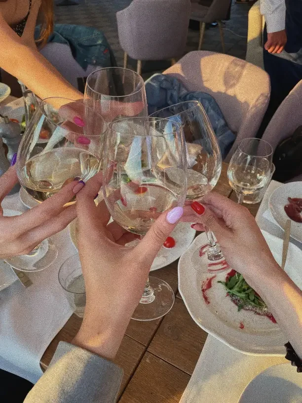 Fun Christmas gifts for young adults with friends clinking glasses at a holiday dinner.