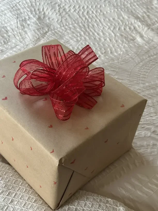 Gifts for nanny Christmas with a kraft paper gift box tied with a red bow.