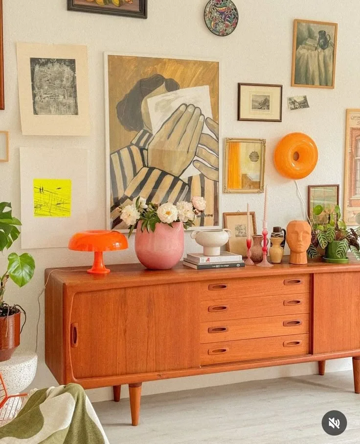 Orange mid century credenza under a colorful gallery wall