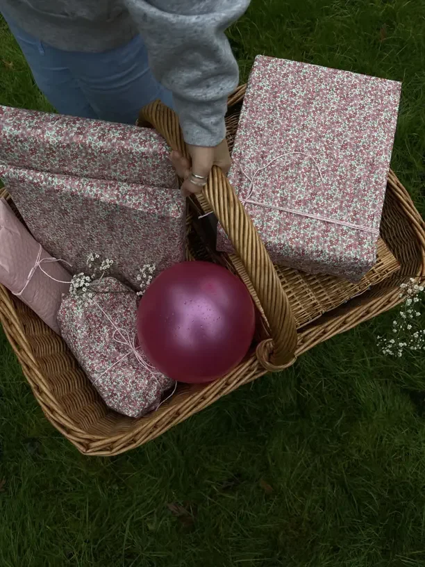 Secret Santa gift basket ideas with a basket of wrapped gifts and a pink ornament.