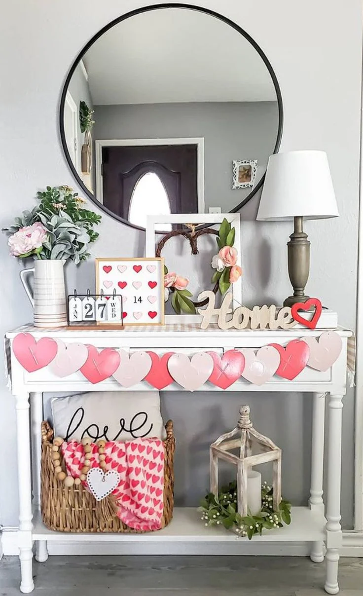 Valentine's console table with a round mirror, pink flowers, candles and heart decor